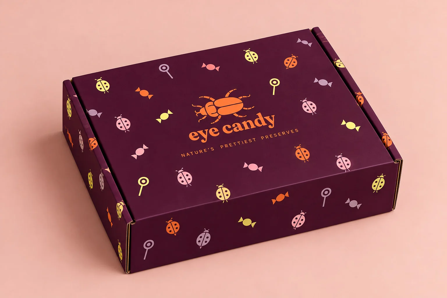 A plum Eye Candy shipping box printed with the beetle logo and a pattern of ladybirds, sweets and lollipops